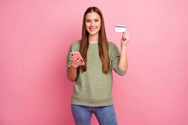 Chica alegre positiva uso smartphone mantenga tarjeta de crédito