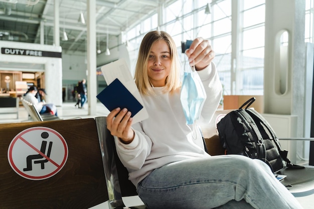 Chica alegre se sienta en la terminal del aeropuerto en sillas