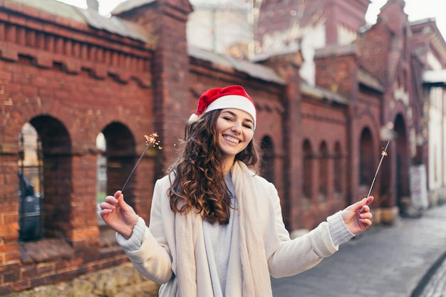 Chica alegre con un sombrero de Navidad sonriendo a la cámara