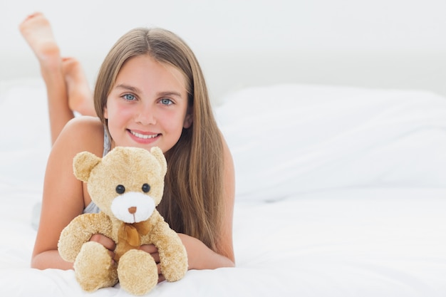 Chica alegre sosteniendo un oso de peluche