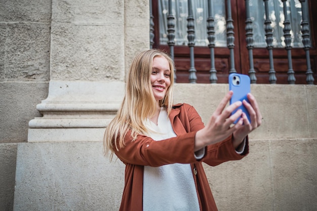 Chica alegre tomándose un selfie con su teléfono para compartirlo con sus seguidores en las redes sociales