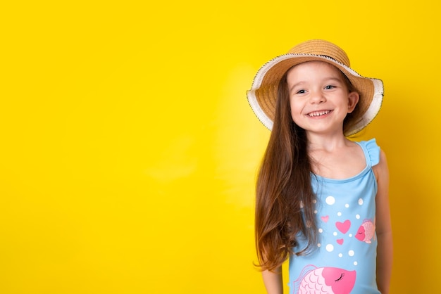 Chica alegre de vacaciones de verano en un traje de baño azul y fondo amarillo sombrero Espacio para texto