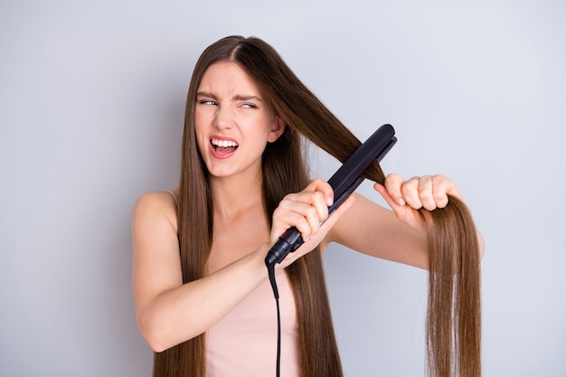 chica alisar el cabello con plancha de pelo