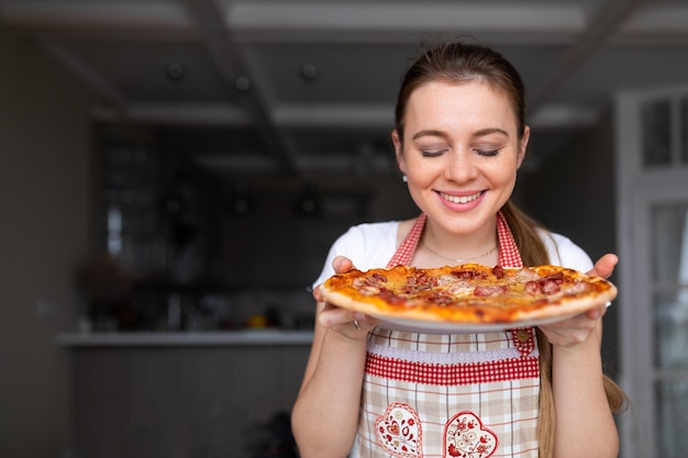 Chica ama de casa con deliciosa pizza en la cocina