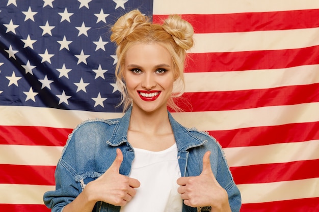 Chica americana. Retrato de feliz de joven sorprendida en el fondo de la bandera de Estados Unidos