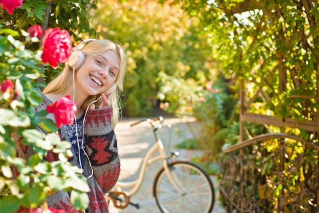 Chica andar en bicicleta por diversión. Rubia disfruta relajarse en el parque o en el jardín. Chica activa con bicicleta. Movimiento y energía. Mujer con bicicleta en jardín floreciente. Actividad de fin de semana. Ocio activo y estilo de vida