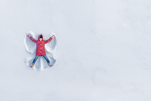 Foto la chica en un ángel de nieve muestra