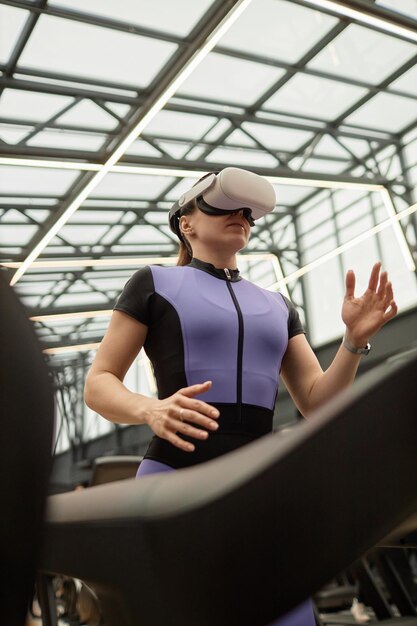Chica de ángulo bajo corriendo en cinta de correr vr