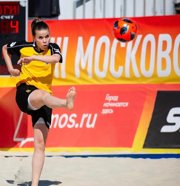 Foto una chica anota un gol en el fútbol de playa descalza