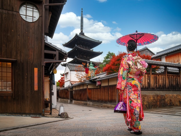 Chica apanesí camina en el viejo mercado de Kyoto y la pagoda boscosa de Yasaka