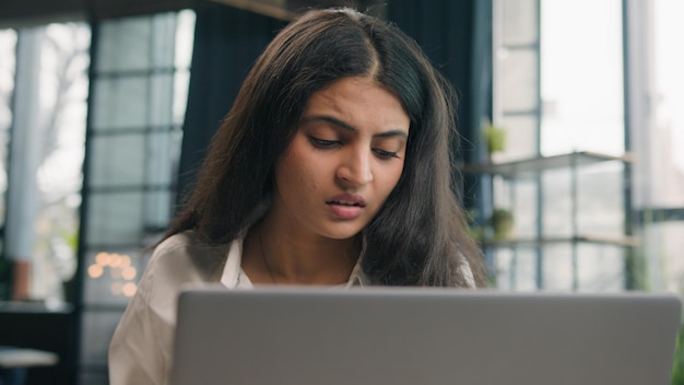 Chica árabe insatisfecha Mujer ansiosa india con computadora trabajando en un problema de negocios en la oficina