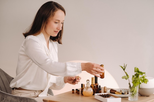 La chica aromaterapeuta está sentada en su oficina, hay aceites esenciales en la mesa.