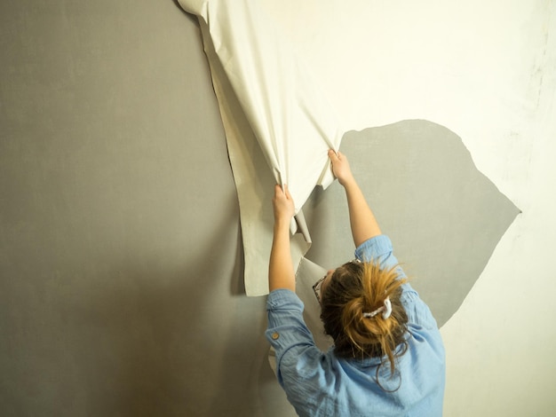 Foto la chica arranca el papel tapiz viejo y hace renovaciones en el apartamento