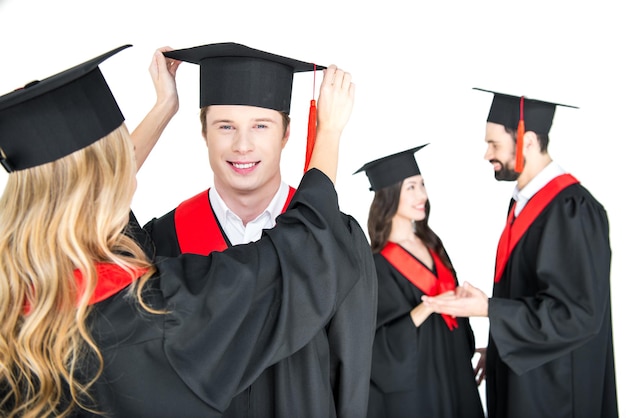 chica arreglando el sombrero de graduación del estudiante 39 aislado en blanco