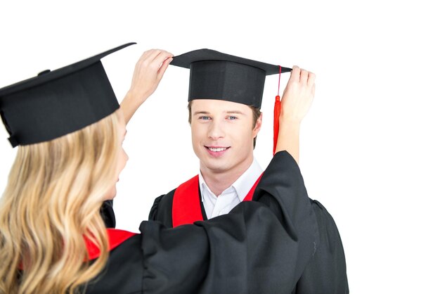 chica arreglando el sombrero de graduación del estudiante 39 aislado en blanco