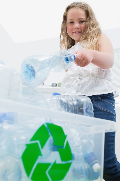 Chica arrojando botellas en caja de reciclaje