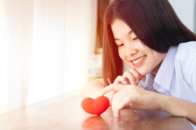 Chica asiática adolescente encantadora universidad linda sonriendo con corazón rojo para el amor juntos el concepto del día de San Valentín