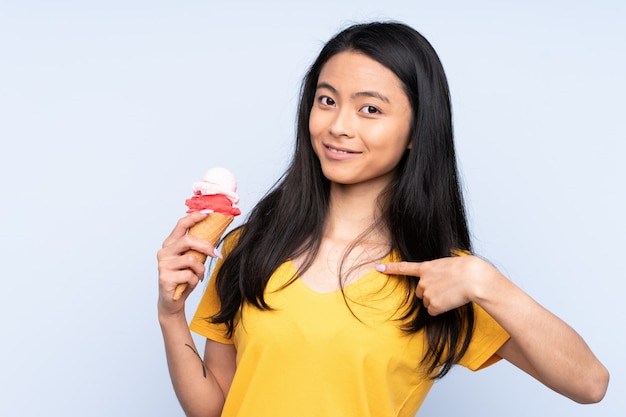 Chica asiática adolescente con un helado de cucurucho aislado en azul