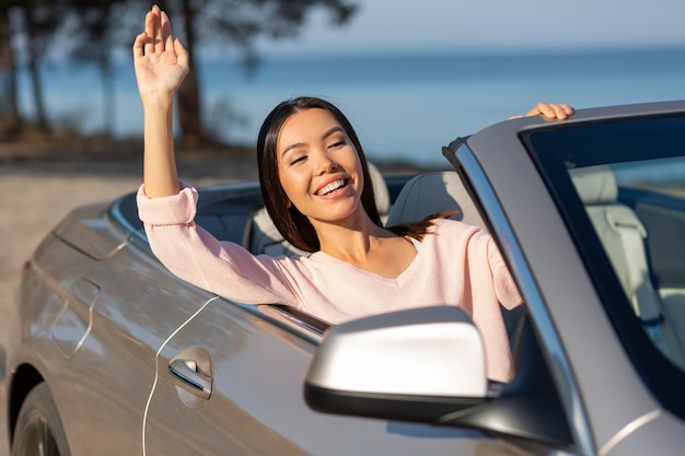 Chica asiática agitando la mano de cabriolet