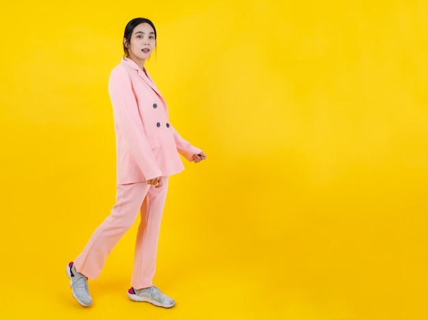 Chica asiática atractiva y linda en una hermosa chaqueta de negocios rosa, pantalones y zapatillas de deporte caminando y sonriendo fácilmente como modelo bonita para la belleza de la mujer, la ropa, la moda y el estilo de vida femenino.
