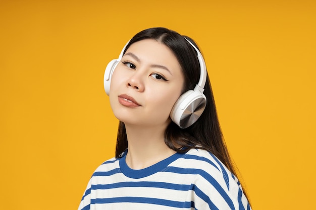 Chica asiática en auriculares sobre un fondo amarillo