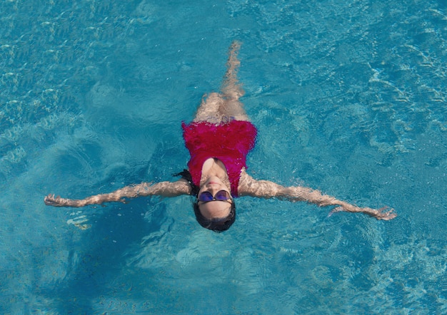 Chica asiática con baño suite y gafas de sol en la piscina