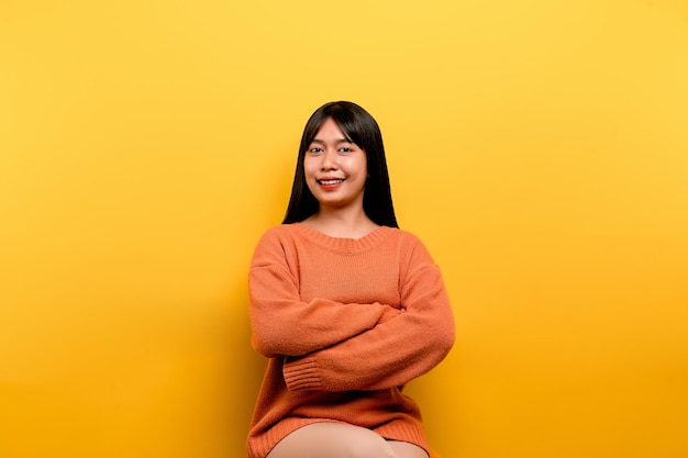 Chica asiática Bonita con un vestido casual naranja de fondo amarillo Celebra la victoria con una sonrisa feliz y la expresión del ganador con una expresión feliz de la mano levantada