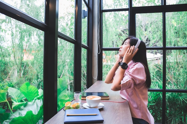 Chica asiática en una cafetería Concepto de tecnología de estilo de vida Mujer asiática usando una aplicación en un teléfono inteligente