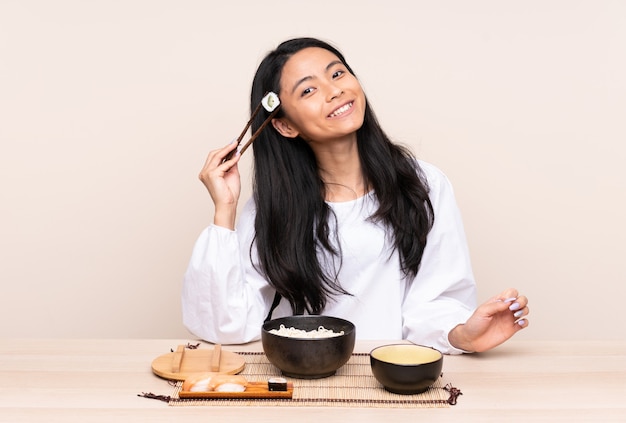 Chica asiática comiendo fideos y sushi