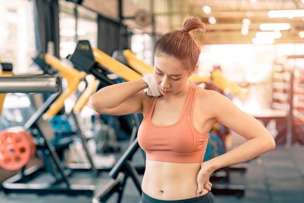 Foto chica asiática descansando del ejercicio en el gimnasio y sudando en su cara