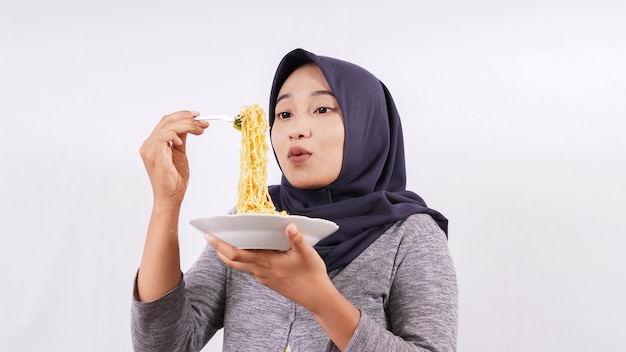 Chica asiática disfrutando felizmente de fideos aislado sobre fondo blanco.