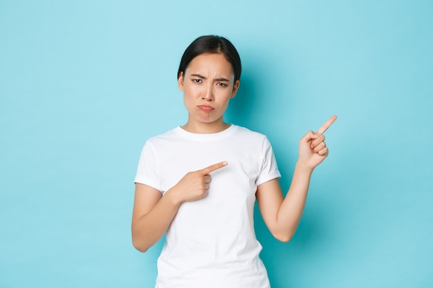 Chica asiática enfurruñada triste decepcionada en camiseta blanca