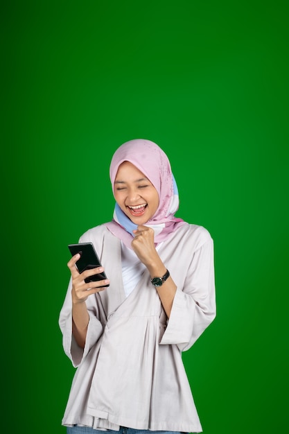 Chica asiática con entusiasmo al mirar la pantalla del teléfono móvil