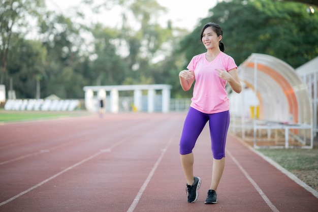 Chica asiática está estirando los músculos calientes de su cuerpo antes de salir a correr al parque