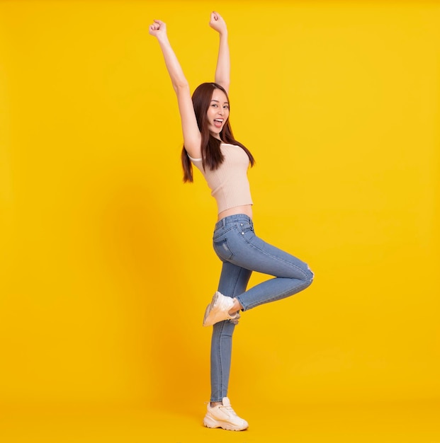 Chica asiática feliz bailando y celebrando aislada sobre amarillo