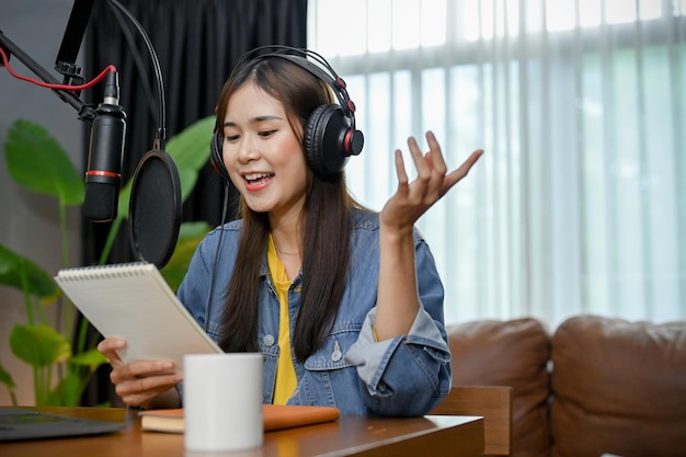 Chica asiática feliz graba un podcast con auriculares y micrófono