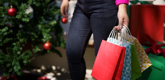 Una chica asiática feliz sostiene bolsas de compras, un regalo de Navidad, una mujer alegre con una venta de invierno de Navidad y Año Nuevo.