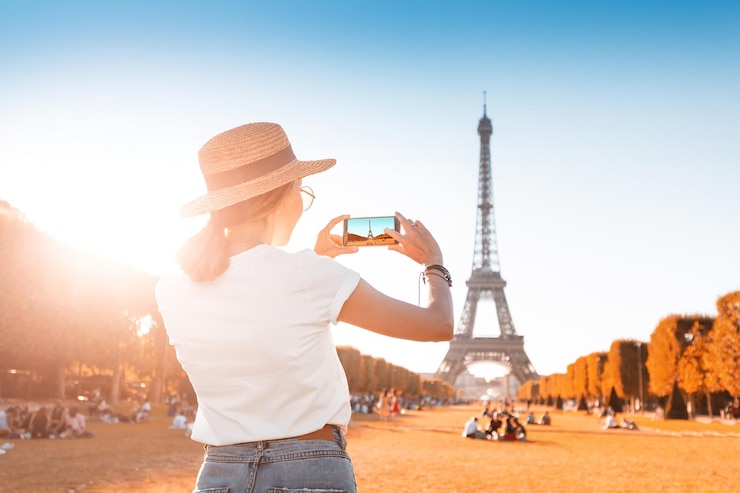 Foto chica asiática feliz toma una foto en su teléfono inteligente en el fondo de la torre eiffel travel