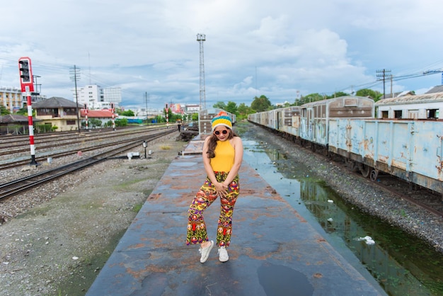 Chica asiática hipster posar para tomar una foto Retrato de moda mujer bonita en el estilo de vida ferroviario de una chica tailandesa adolescente moderna Telas coloridas Gente de Tailandia