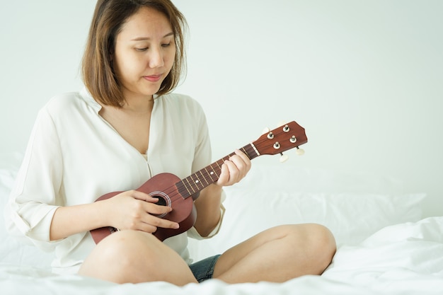 Chica asiática juega el ukelele