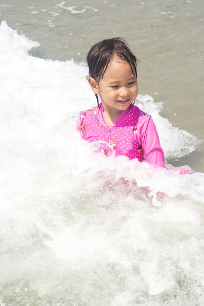 Chica asiática jugando en el mar