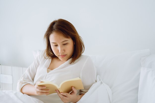 Chica asiática Leer libros después de despertarse por la mañana. Te hace sentir brillante