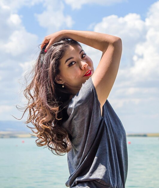 Chica asiática con el pelo largo posando contra el cielo