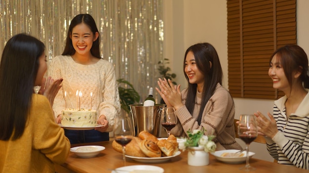 Foto chica asiática sonriendo y disfrutando de una fiesta de cumpleaños sosteniendo un pastel de aniversario