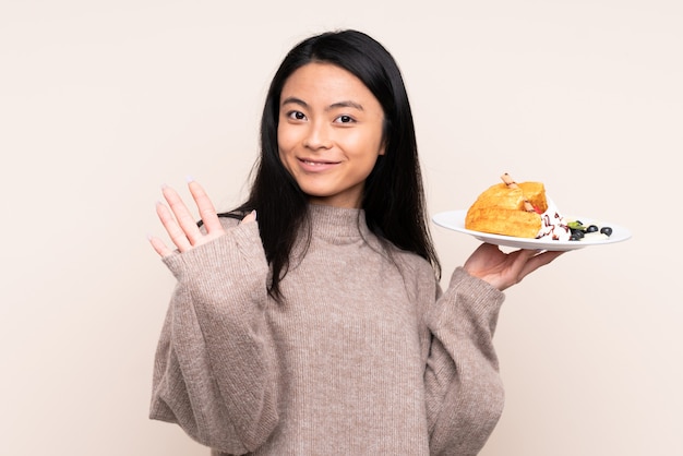 Chica asiática sosteniendo un plato con waffles