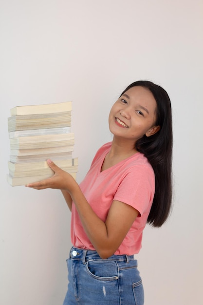 Chica asiática sostiene un libro en su brazo sobre fondo whiye Chica estudiante