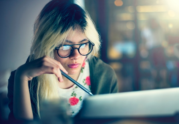 Chica asiática trabajando en una computadora portátil en la oscuridad