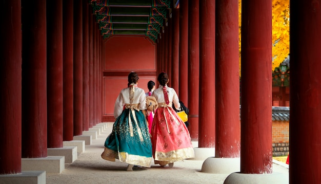 Chica asiática en vestido de hanbok caminar en otoño deja park