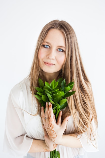 Chica de aspecto europeo en ropa brillante con ramas verdes.