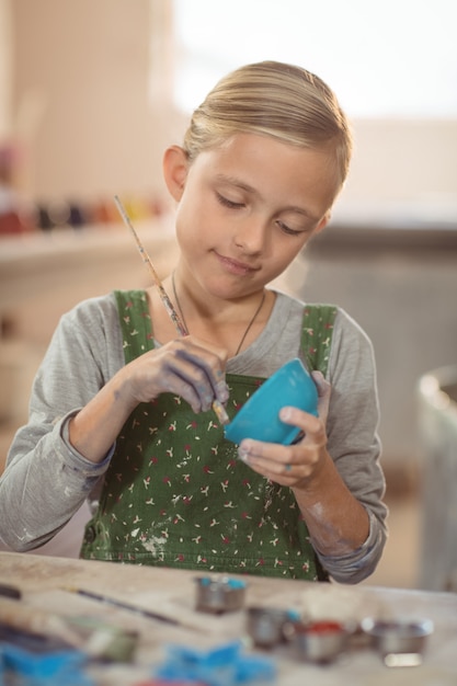 Chica atenta pintando en un tazón